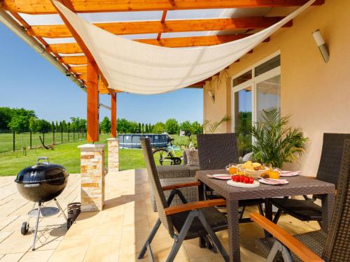 a patio with a grill and a table and chairs at Holiday Home Paola by Interhome in Balatonszemes