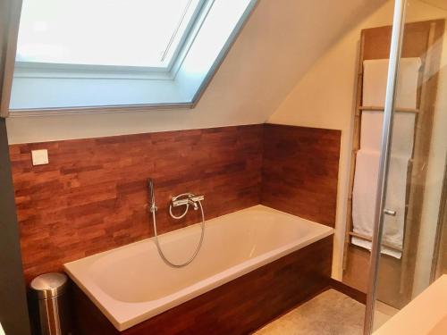 een badkamer met een bad en een dakraam bij Chambre d'hôte Saint-Symphorien Mons in Bergen