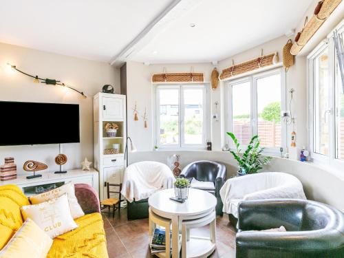 un salon avec un canapé, des chaises et une télévision dans l'établissement Holiday Home Ty Moutic by Interhome, à Kerlouan