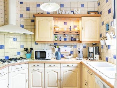 une cuisine avec des placards blancs et du carrelage bleu dans l'établissement Holiday Home Ty Moutic by Interhome, à Kerlouan