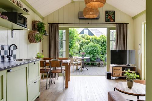 a kitchen and living room with a table and chairs at Cottage 'Onder de boompjes' in Oostwoud