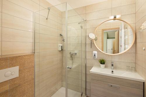 ein Bad mit einer Dusche, einem Waschbecken und einem Spiegel in der Unterkunft Admiral Family Resort in Keszthely