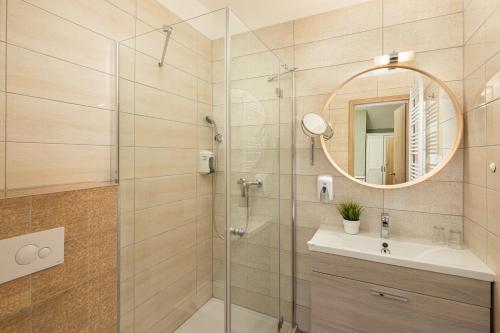 a bathroom with a shower with a sink and a mirror at Admiral Family Resort in Keszthely