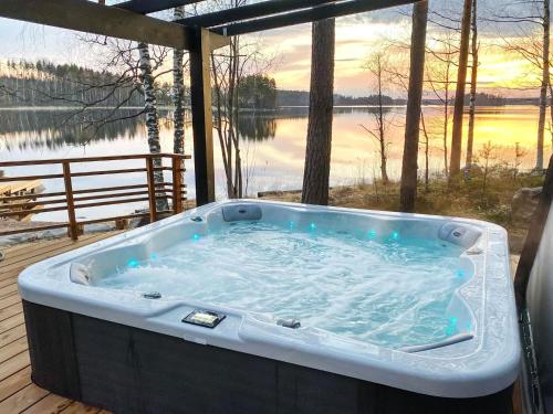a hot tub on a deck with a view of a lake at Holiday Home Villa saimaan joutsenlahti by Interhome in Äitsaari