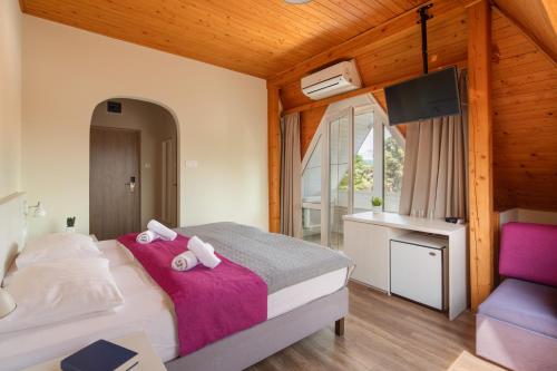a bedroom with a bed with a purple blanket at Admiral Family Resort in Keszthely