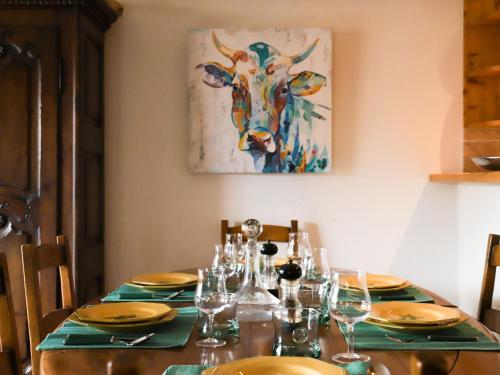 a dining room table with a cow painting on the wall at Apartment Résidence Bristol 4 by Interhome in Villars-sur-Ollon