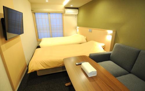 Cette petite chambre comprend un lit, une table et un canapé. dans l'établissement HIZ HOTEL Kyoto Nijo Castle - Vacation STAY 12537v, à Kyoto
