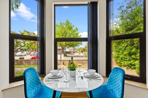 a dining room with a table and blue chairs and windows at West One Studios in Nottingham