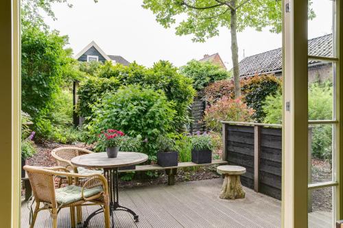 un patio con tavolo e sedie e un giardino di Cottage 'Onder de boompjes' a Oostwoud