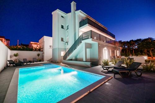 a large swimming pool in front of a house at Apartments Lacrima near the sea in Šilo