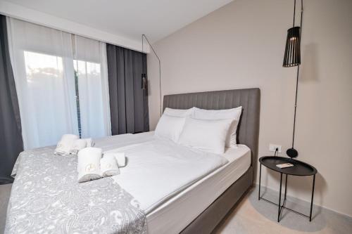een slaapkamer met een bed met witte lakens en een tafel bij Luxury Apartments Villa Lacrima in Šilo