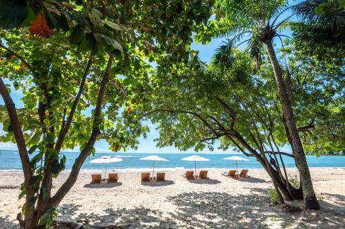a beach with chairs and umbrellas and the ocean at Colibri Beach Villas in Ilha de Boipeba