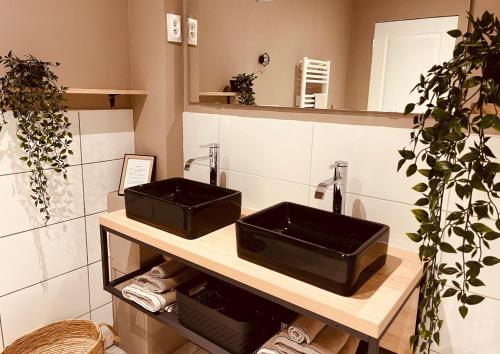 une salle de bains avec deux lavabos noirs sur un comptoir dans l'établissement Bleu Horizon, à Quiberville