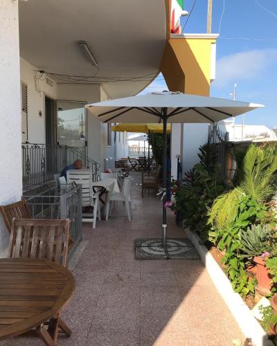 a patio with an umbrella and tables and chairs at Albergo Europa in Marina di Mancaversa
