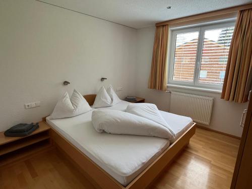 Schlafzimmer mit einem Bett mit weißer Bettwäsche und einem Fenster in der Unterkunft Appartement Bellevue in Damüls