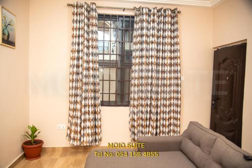 a living room with a couch and two windows at Mojo Apartment, Tema in Tema