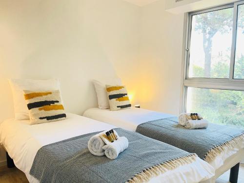 two beds with towels on them in a room with a window at Très bel appartement face au port Santa -Piscine in Saint-Raphaël