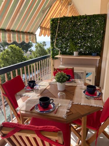 uma mesa de madeira com cadeiras vermelhas na varanda em Appartement rénové, terrasse vue mer em Cagnes-sur-Mer