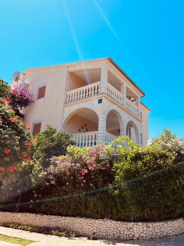 a building with a balcony and some flowers at Apartmani Mate in Rogoznica