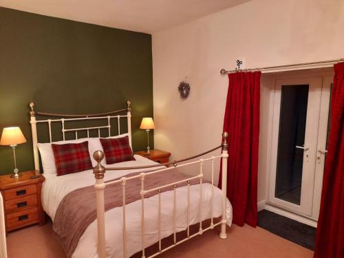 1 dormitorio con 1 cama con cortinas rojas en Underhill Holidays - Underhill Holiday Cottage en Whitby
