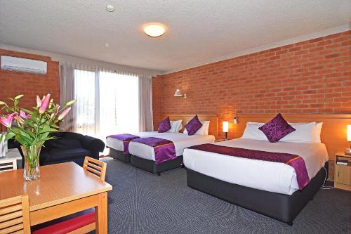 Habitación de hotel con 2 camas y pared de ladrillo en Main Lead Ballarat Motel, en Ballarat