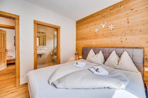 a bedroom with a large white bed with two towels at Chaletdorf am Sonnenhang in Neukirchen am Großvenediger