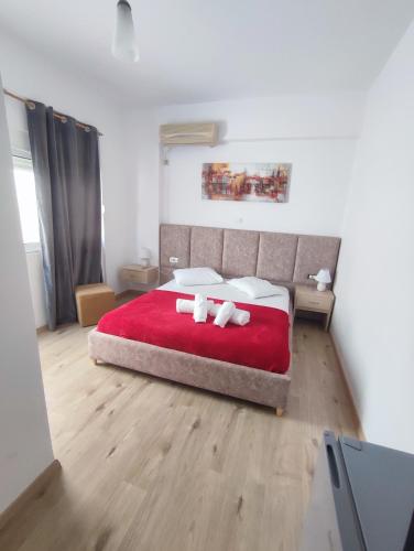 a bedroom with a red bed with two towels on it at Lazaris kwstas Rooms in Himare