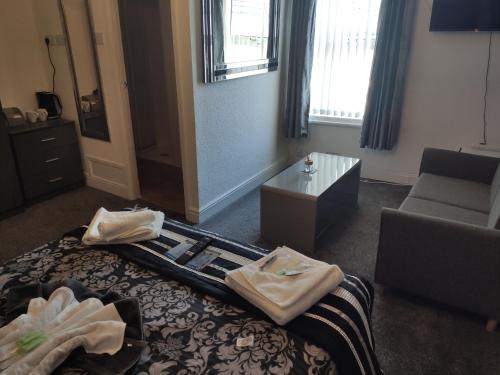 a room with a bed and a couch and a table at Mardi Gras Hotel in Blackpool