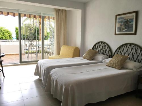 two beds in a hotel room with a balcony at Apartamentos Bahia in Benidorm