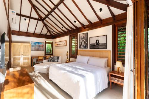 a bedroom with a white bed and a couch at Colibri Beach Villas in Ilha de Boipeba