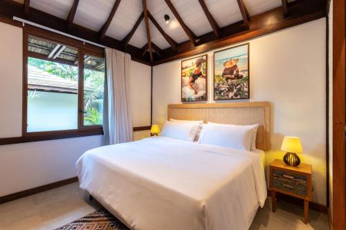 a bedroom with a large white bed and two windows at Colibri Beach Villas in Ilha de Boipeba