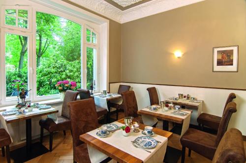 um restaurante com mesas e cadeiras e uma janela em Hotel Miramar em Hamburgo