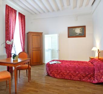 een slaapkamer met een rood bed en een tafel en stoelen bij Villa Médicis AUTUN in Autun