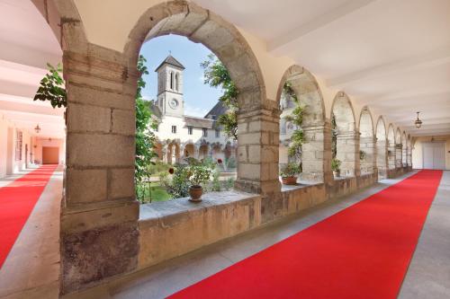 un couloir vide avec un tapis rouge et une église dans l'établissement Villa Médicis AUTUN, à Autun