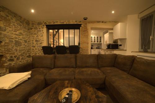 a living room with a brown couch and a table at Maison atypique centre bourg 15kms du PDF et Parc Maulévrier in Mauléon