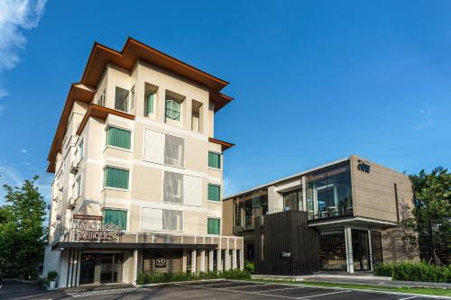 a tall white building next to a building at Nakornping Boutique Hotel in Ban Saia