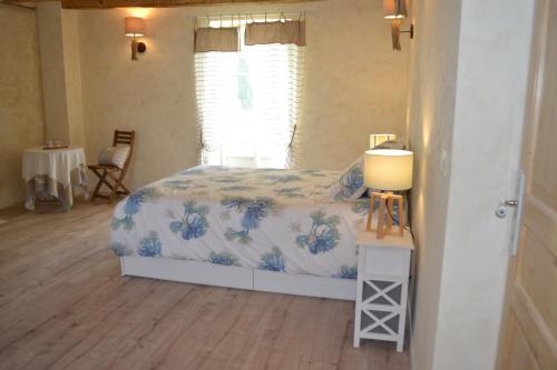 ein Schlafzimmer mit einem Bett und einem Tisch mit einer Lampe in der Unterkunft Escale à Villeperdue chambre Hellulaug in La Barillonnerie