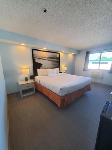 a bedroom with a large bed and two lamps at Coastal Inn & Suites in Wilmington