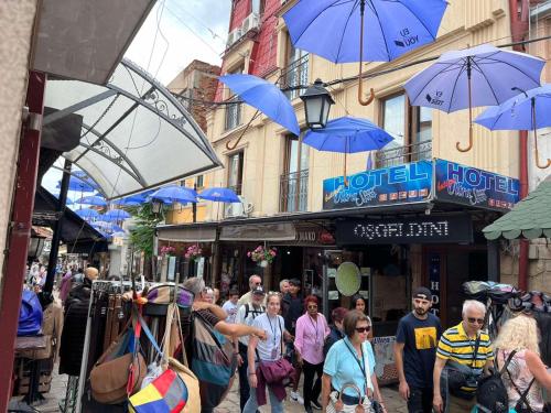 a crowd of people walking down a street with blue umbrellas at Hotel Ultra Star in Skopje