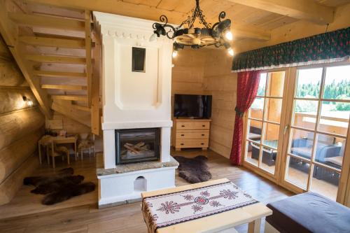 a living room with a fireplace in a log cabin at Bajkowa Osada Murzasichle domek z jacuzzi in Murzasichle