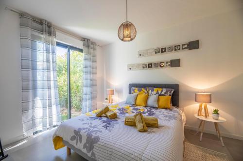 Un dormitorio con una cama con almohadas amarillas y una ventana. en Porto Vecchio Villa Bagatelle 8 personnes, en Porto Vecchio