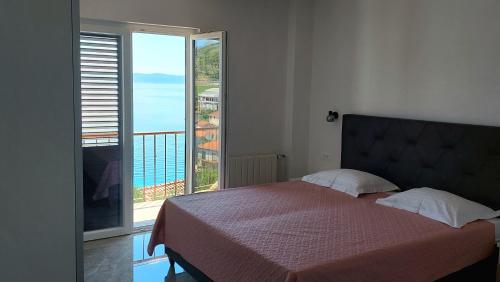 a bedroom with a bed and a balcony with a view at Apartman Dado Podgora in Podgora