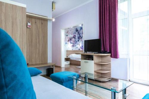uma sala de estar com um sofá azul e uma televisão em Hotel Ezeroto em Stara Zagora