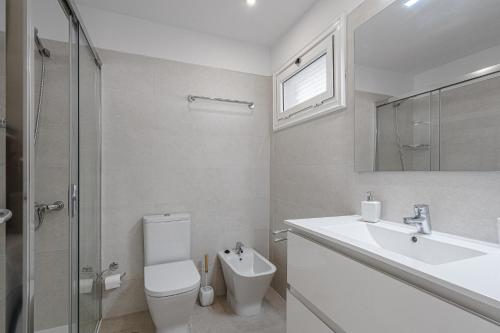 een witte badkamer met een toilet en een wastafel bij Lovely studio, La Pinta beach, Complex Los Geranios in Adeje