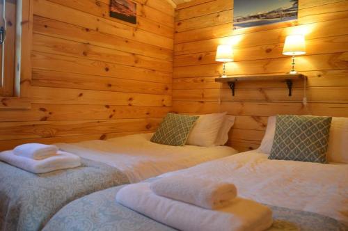 two beds in a room with wooden walls at Seillean Trang in Saasaig