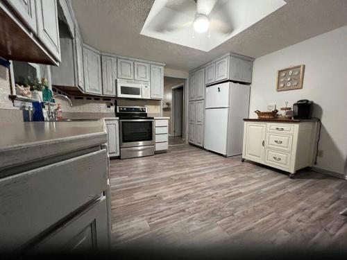 a large kitchen with white appliances and wooden floors at Cottage near Cedar Point and downtown Sandusky in Sandusky