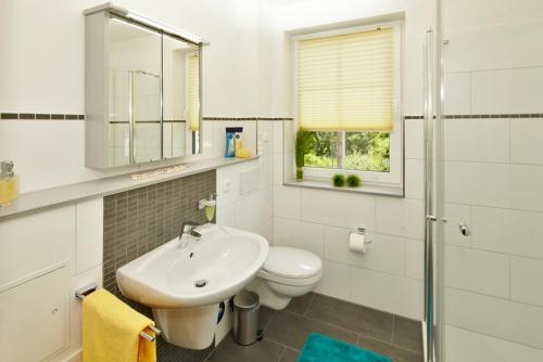 Baño blanco con lavabo y aseo en Ferienwohnung Kargoll Wydra in Heringsdorf en Heringsdorf