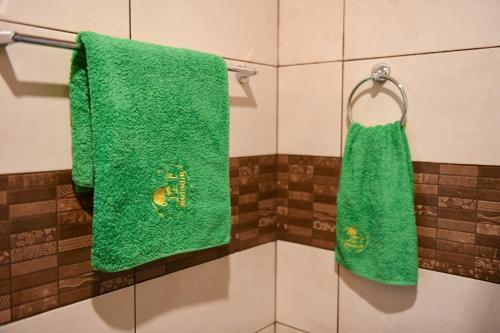 2 toallas verdes colgadas en un estante del baño en Manana Guesthouse, en Marmarik