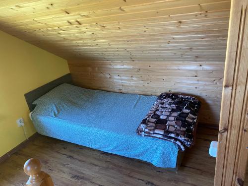 a bed in a room with a wooden wall at Strazdiņi in Saraiķi