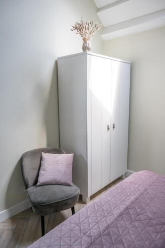 a bedroom with a bed and a chair and a cabinet at Holiday home de Stamhoeve in Biezenmortel